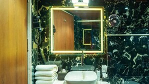 A bathroom with a marble sink, a large mirror, and a towel rack. - Clarks Inn Suites Hyderabad (Hyderabad)