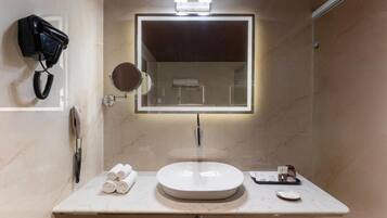 A bathroom with a round sink, a mirror, a hairdryer, and a towel rack.