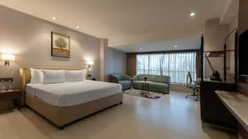 A hotel room with a bed, a desk, a chair, a TV, and a window with curtains.