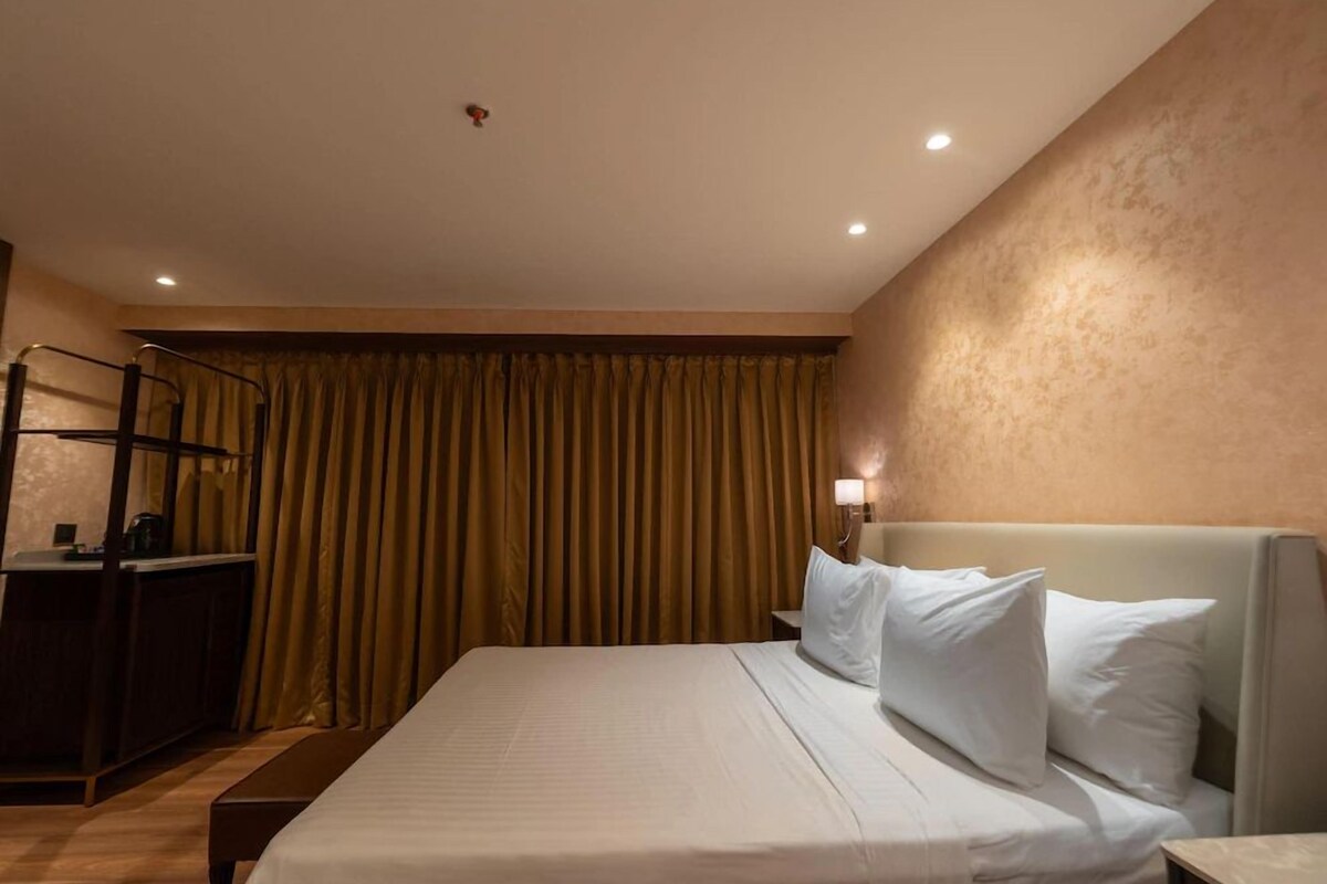 Ein Hotelzimmer mit Bett, Schreibtisch, Stuhl und Vorhang.