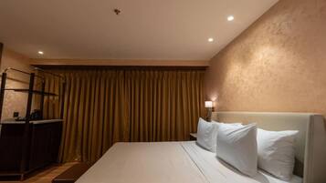 A hotel room with a bed, a desk, a chair, and a curtain.