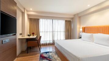 A hotel room with a bed, desk, chair, and a television.