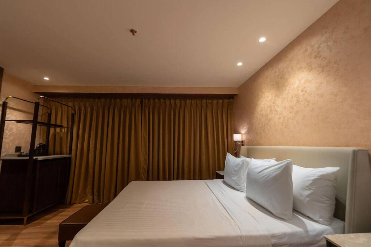 A hotel room with a bed, a desk, a chair, and a curtain.