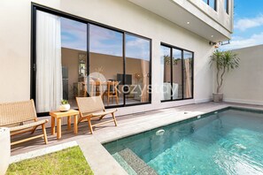 A modern house with a pool, large sliding glass doors, and outdoor furniture. - Surio Villa by Kozystay - Nusa Dua (Kutuh)