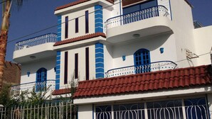 A two-story building with balconies, a red-tiled roof, and a white facade. - Studio mit Pool, Garten und Dachterrasse by Interhome (Luxor)