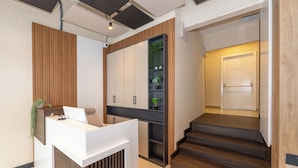 A reception desk with a white counter and wooden paneling, a shelving unit with plants, and a staircase leading to an upper level. - Taksim YEZ Hotel (Istanbul)