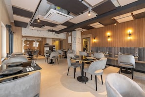A modern restaurant with round tables, grey upholstered chairs, and a wooden accent wall. - Taksim YEZ Hotel (Istanbul)