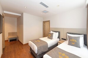 A hotel room with two beds, a bench, and a wooden door. - Taksim YEZ Hotel (Istanbul)