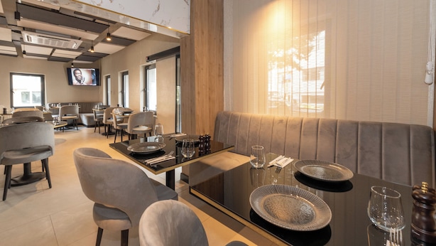 A modern dining area with a long table, cushioned seating, and a television screen. - Taksim YEZ Hotel (Istanbul)