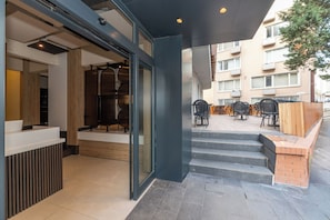 A modern building with a reception desk, a staircase leading to an outdoor seating area, and a view of a residential building in the background. - Taksim YEZ Hotel (Istanbul)