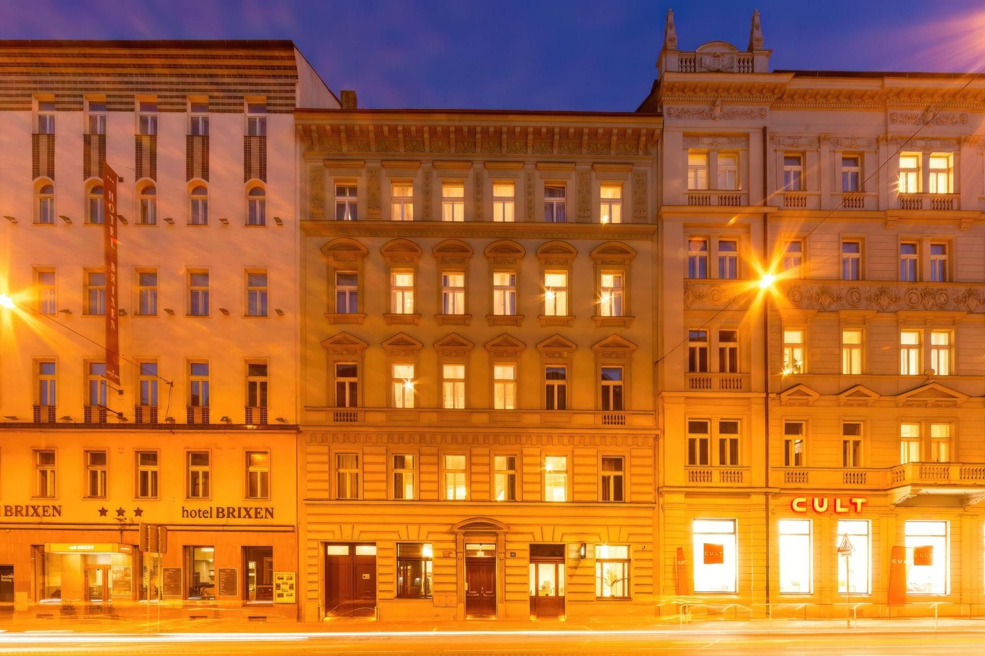 Una hilera de edificios históricos con ventanas iluminadas y carteles que indican 'hotel BRIKEN' y 'CULT'.