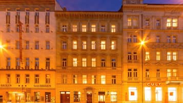 Una hilera de edificios históricos con ventanas iluminadas y carteles que indican 'hotel BRIKEN' y 'CULT'.