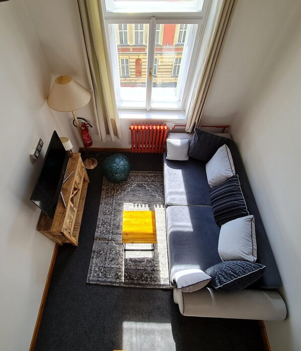 A cozy living room with a sofa, a coffee table, a lamp, a radiator, and a view of the outside. - Hotel S42 (Prague)