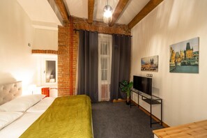 Una habitación con una cama, un televisor, una planta y un cuadro de un paisaje urbano.
