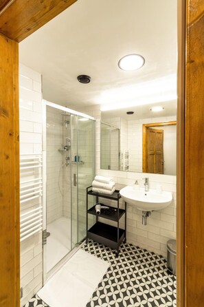 A modern bathroom with a glass-enclosed shower, a white sink, and a patterned floor. - Hotel S42 (Prague)