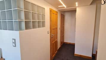 Un couloir doté d’un sol recouvert de moquette, de portes en bois et d’un mur orné de panneaux de verre dépoli.