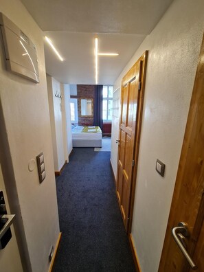 A narrow hallway leading to a bedroom with a bed, a mirror, and a window. - Hotel S42 (Prague)