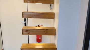 A wooden staircase with a handrail and a red fire extinguisher on the wall.