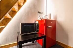 A kitchenette with a microwave, a red refrigerator, and a wooden table. - Hotel S42 (Prague)