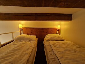 Una habitación con dos camas individuales, cabecero de madera y lámparas de noche.