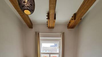Habitación acogedora con sofá, un mueble bajo de televisión de madera, lámpara y ventana con vistas a edificios.