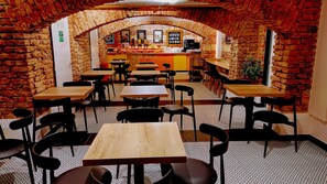 A restaurant with brick walls, multiple tables and chairs, a counter, and a tiled floor. - Hotel S42 (Prague)