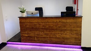 A reception desk with a laptop, a plant, and a speaker. - Hotel S42 (Prague)