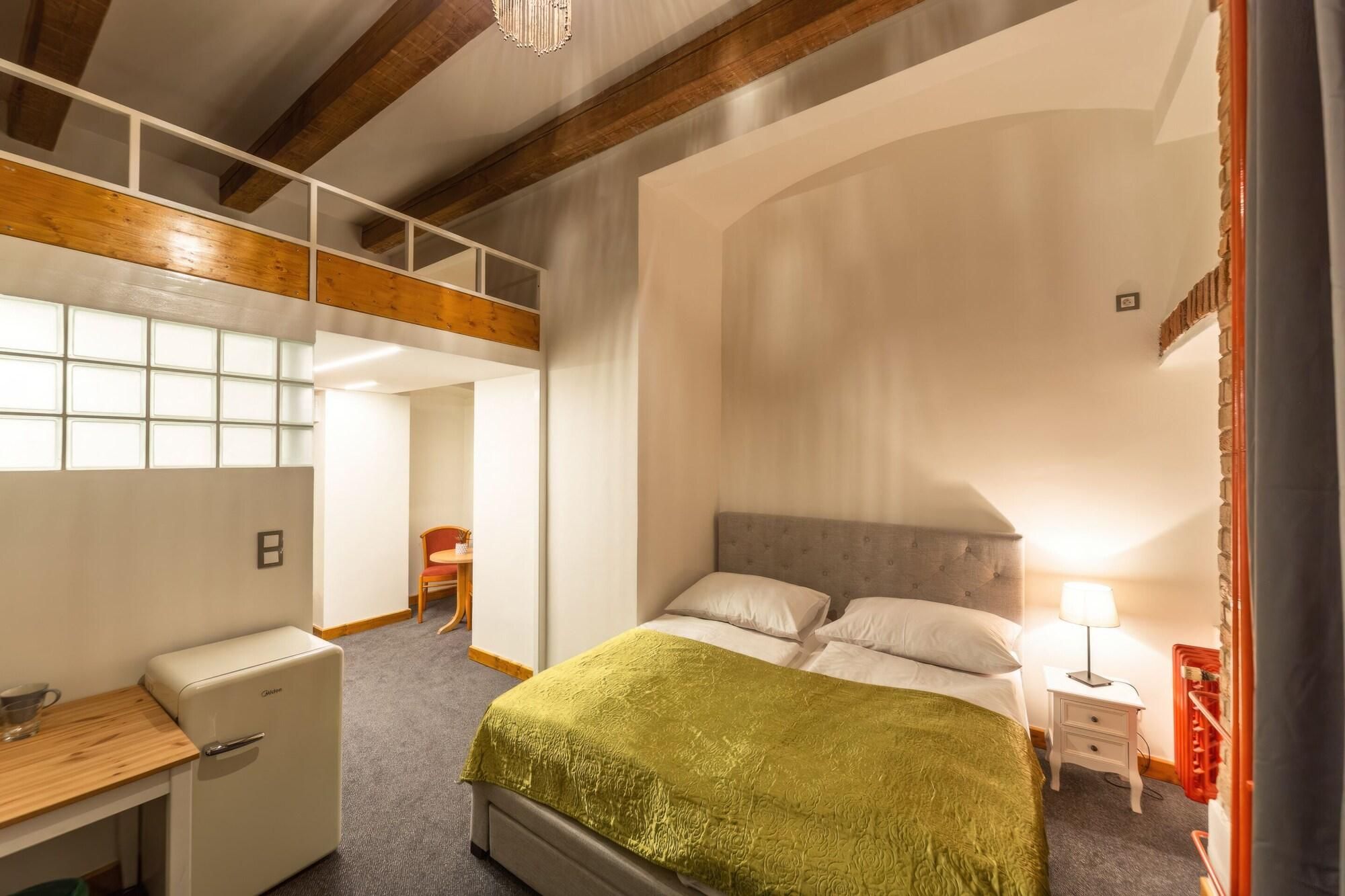 Un dormitorio con cama, mesita de noche, lámpara y un escritorio con silla.
