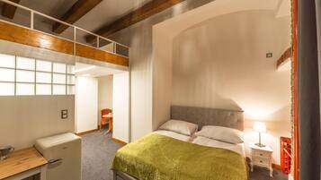 Un dormitorio con cama, mesita de noche, lámpara y un escritorio con silla.