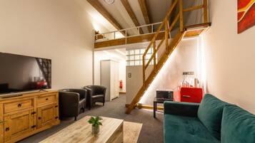 Una sala de estar moderna con televisión, muebles de madera, un sofá y una escalera.