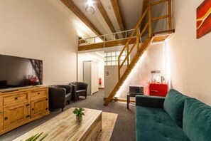 A modern living room with a TV, wooden furniture, a sofa, and a staircase. - Hotel S42 (Prague)