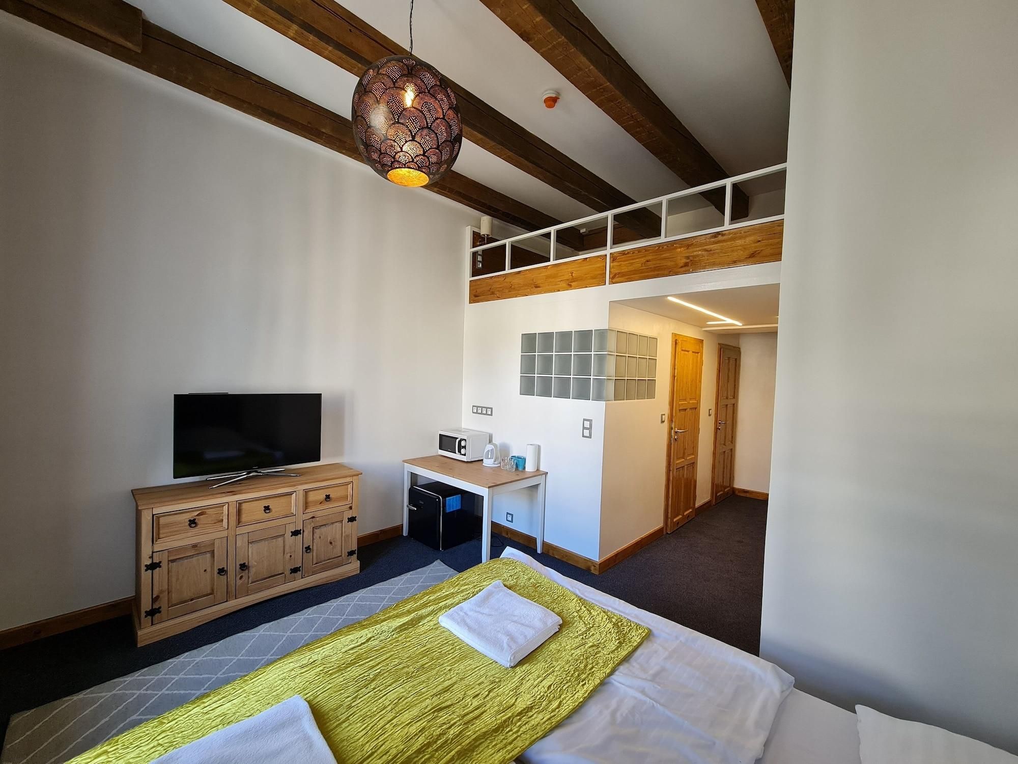 Hotelkamer met een bed, een televisie, een houten kast, een bureau met een magnetron en een hanglamp.