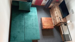 A room with a teal sofa, a wooden chest of drawers, and a small wooden table. - Hotel S42 (Prague)