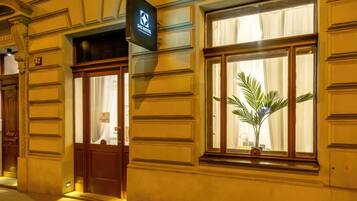 Entrada de un hotel con un cartel que dice 'S42 Hotel', una puerta que indica 'Apartamentos para Huéspedes' y una ventana con una planta.
