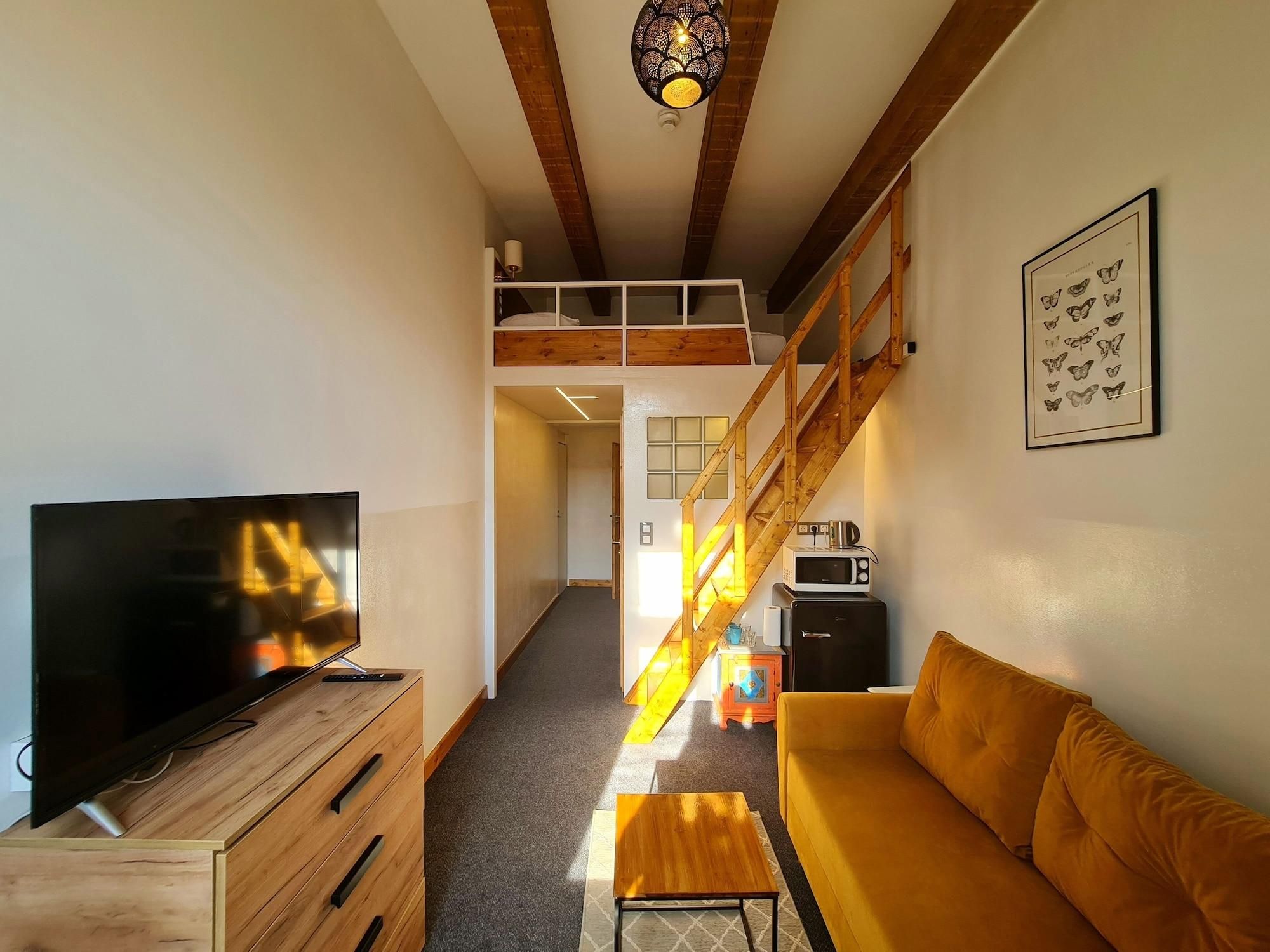 Un espacio habitable moderno con televisor, muebles de madera, un sofá, una escalera y una lámpara en el techo.