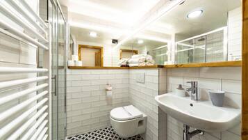 Un baño moderno con cabina de ducha de vidrio, inodoro blanco, lavamanos con espejo y suelo estampado.
