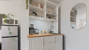 A compact kitchen with white cabinetry, a microwave, a coffee maker, and a sink. - Modern, Quiet, Fully Furnished Suite in the Heart of Lower Lonsdale (North Vancouver)