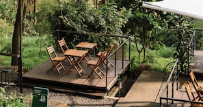 A wooden deck with a table and chairs, surrounded by lush greenery. - Bobocabin Pacet, Mojokerto (Pacet)