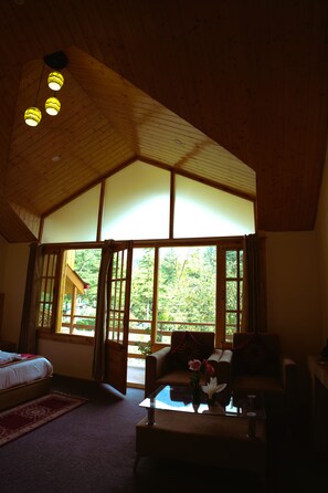 A room with a large window, a bed, a sofa, and a coffee table. - Persimmon Farmstead (Manali)