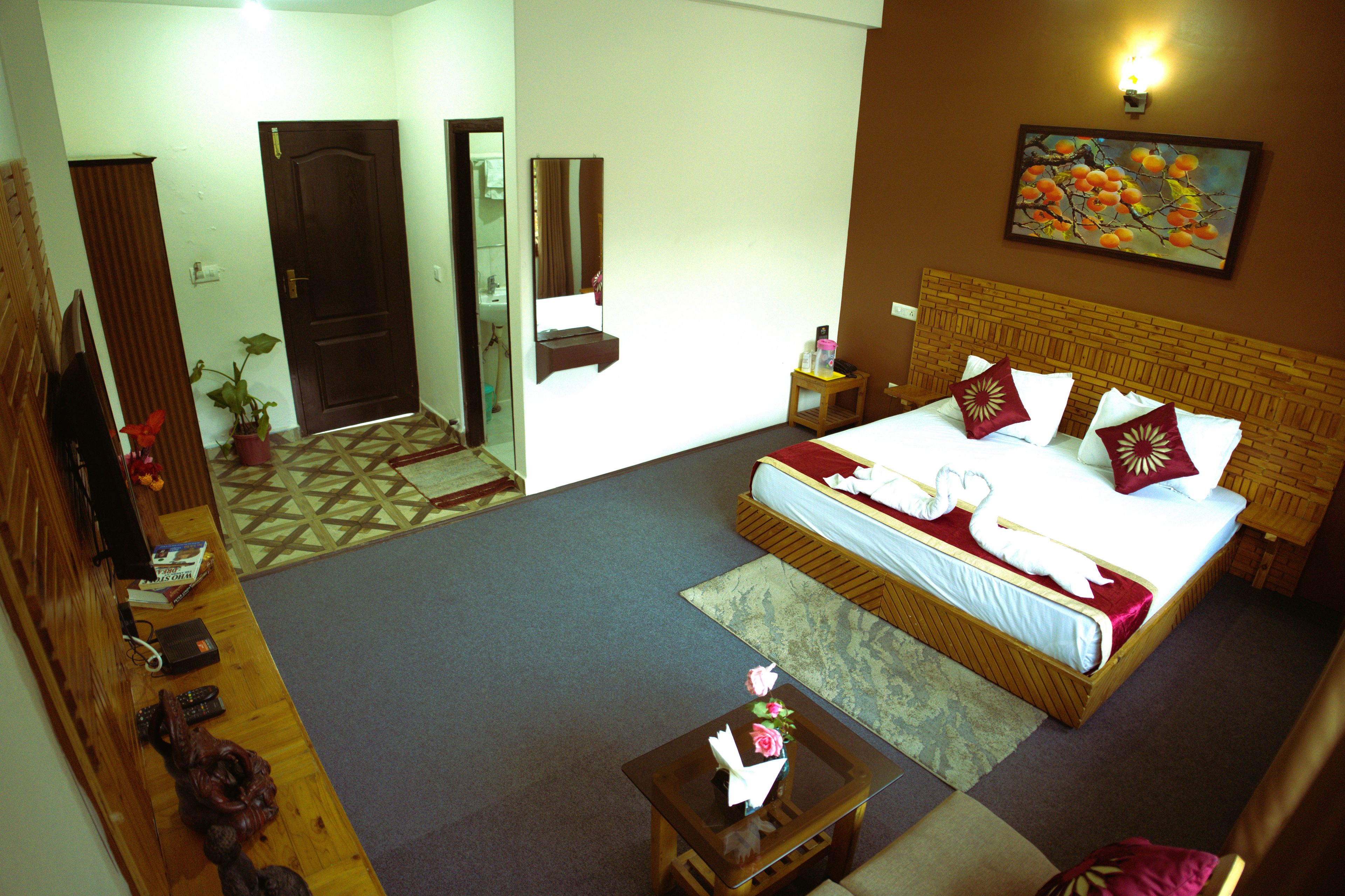 Habitación de hotel con una cama grande, una mesita pequeña, un espejo y un cuadro en la pared.