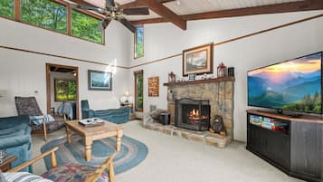 A spacious living room with a stone fireplace, a television, and comfortable seating.