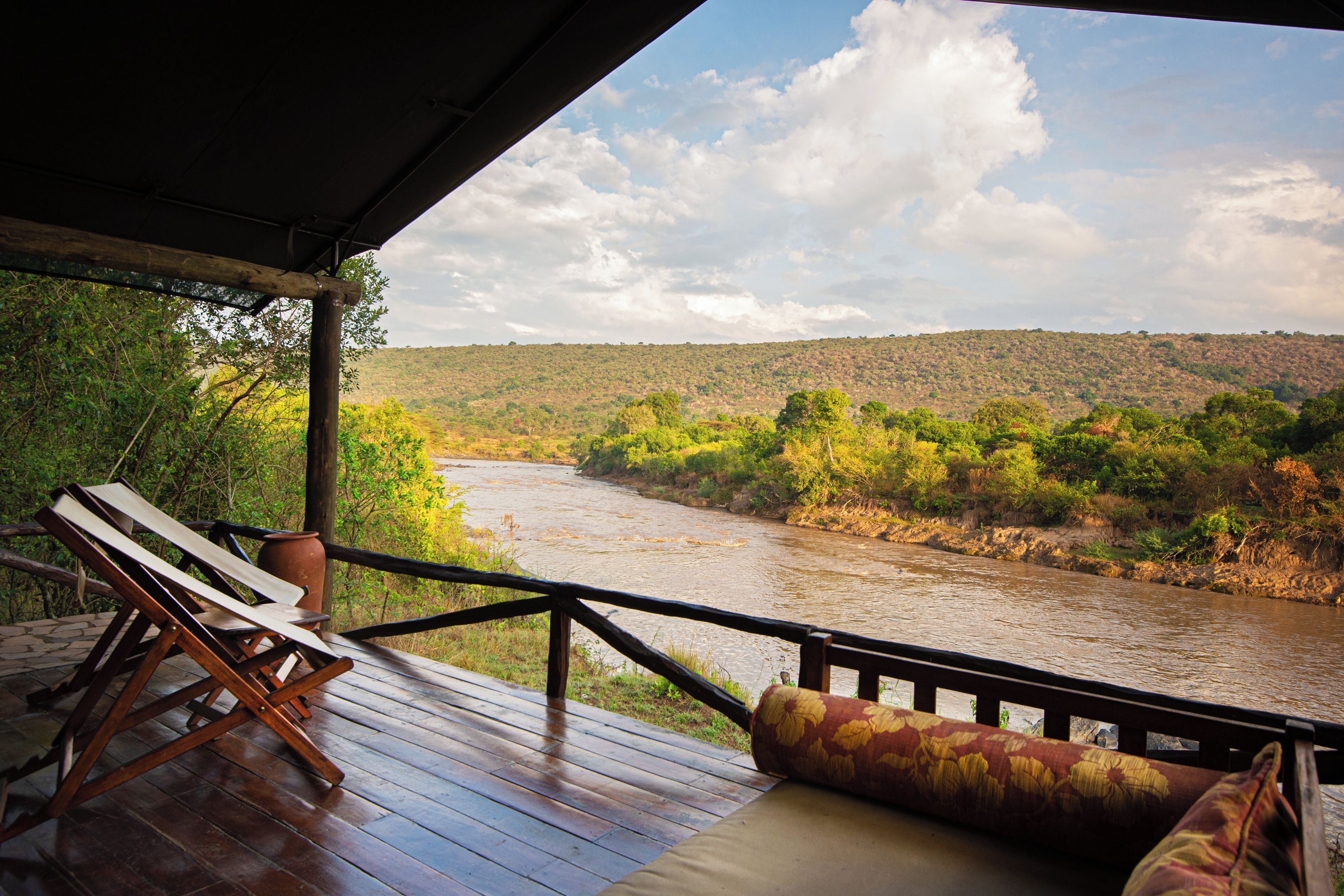 A wooden deck with a view of a river and hills.