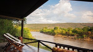 Una terraza de madera con vistas a un río y colinas.