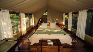 Una habitación con carpa, una cama, un sofá y una mesa con una revista.