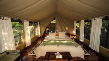 A tented room with a bed, a sofa, and a table with a magazine.