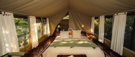 Una habitación con carpa, una cama, un sofá y una mesa con una revista.