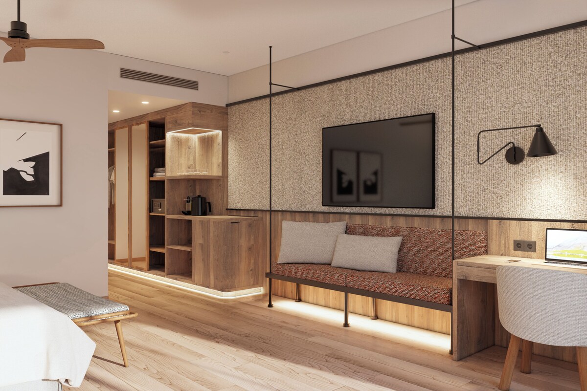 Een moderne slaapkamer met een bed, bureau, bank en televisie.