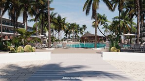 Ein Poolbereich eines Resorts mit Palmen, Liegestühlen und einer Hütte.