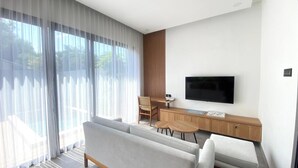 A modern living room with a sofa, a TV mounted on the wall, and a dining area with a table and chairs. - Terra House B1 (Kedonganan)