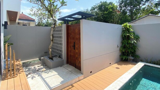 A private pool area with a wooden deck, a small garden with a tree, and a covered seating area. - Terra House B1 (Kedonganan)
